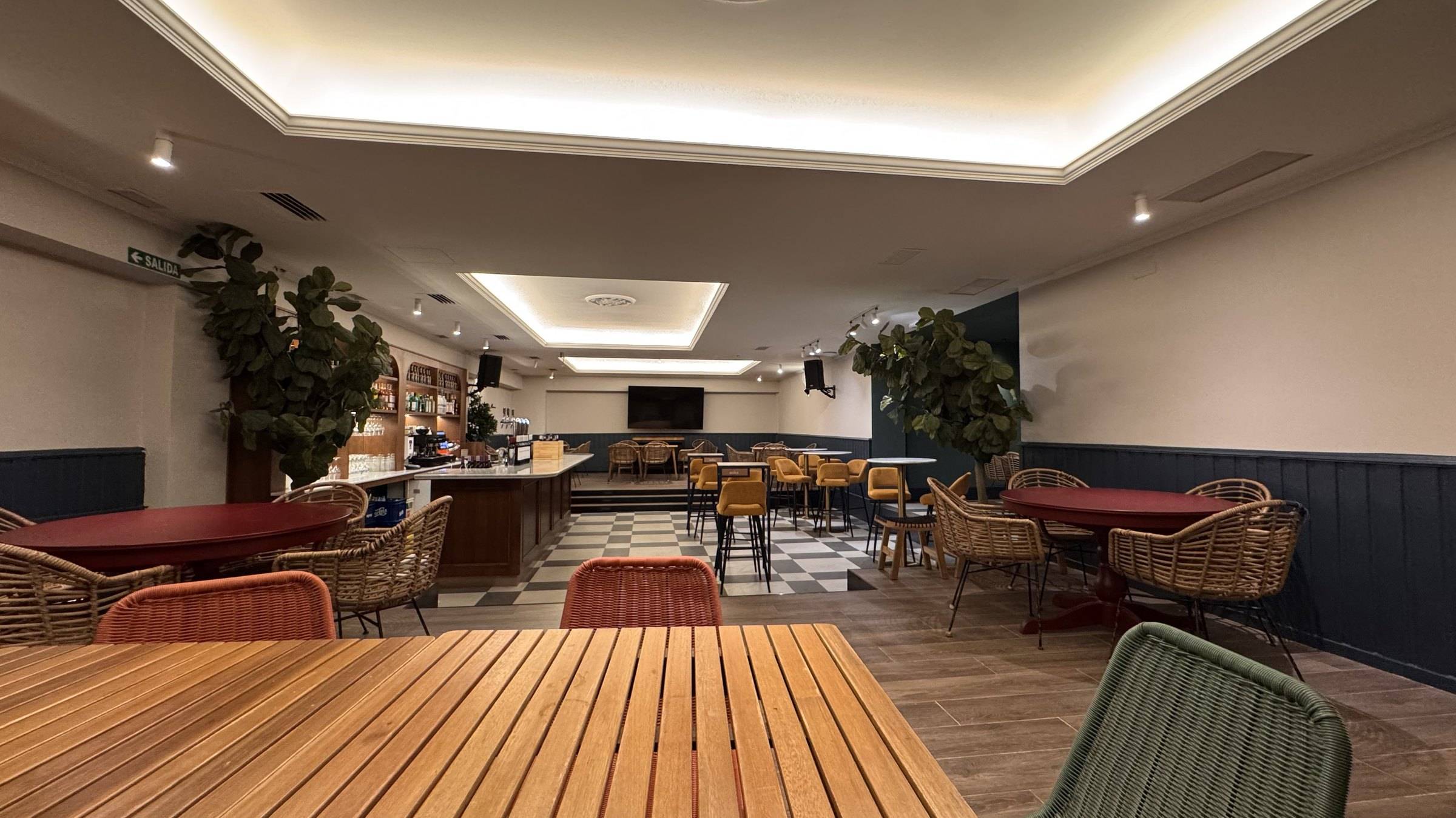 Salón del Club en la planta baja con suelo ajedrezado, butacas de mimbre y luz cálida