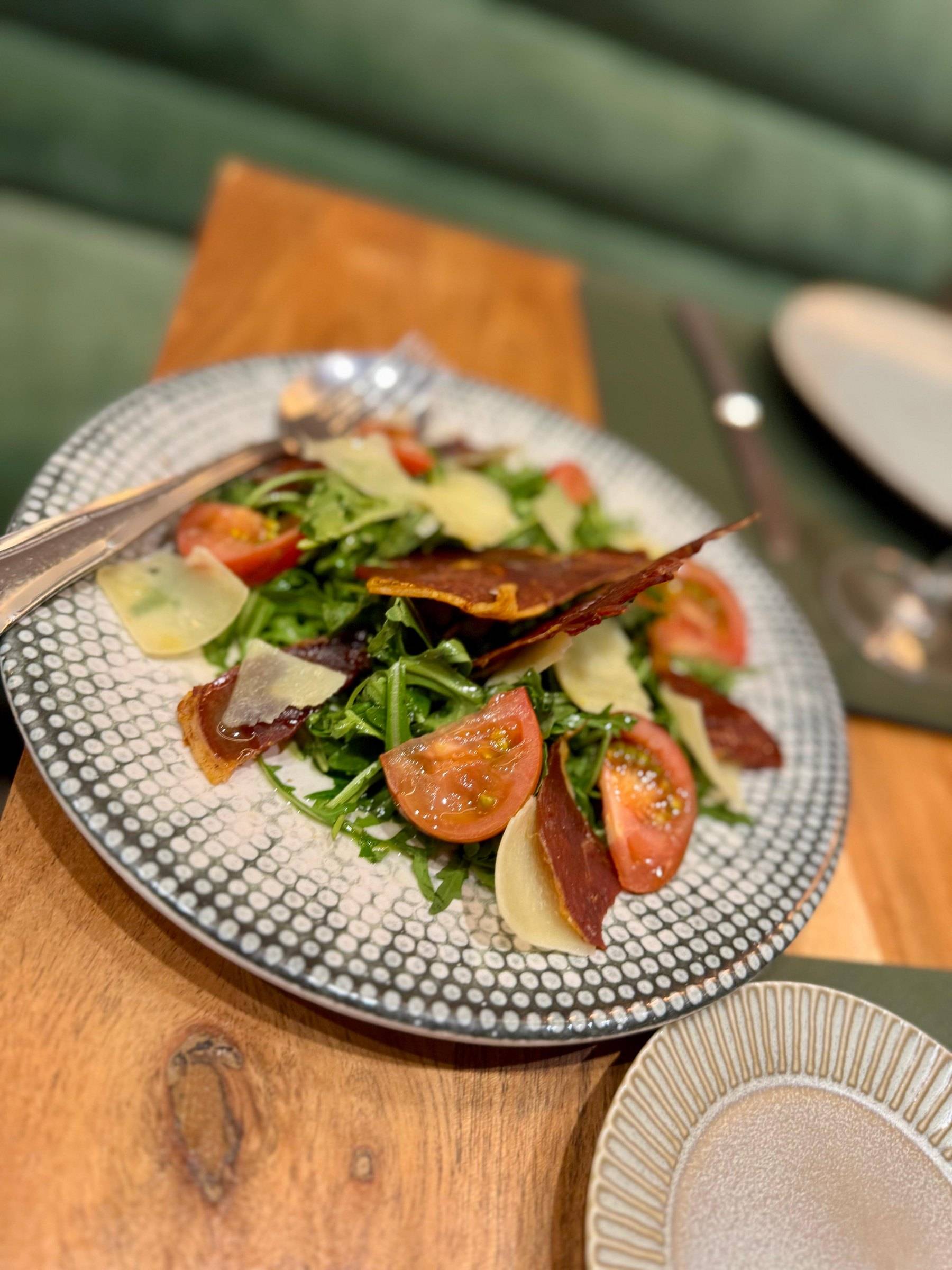 Ensalada de rúcula con tomate, parmesano y crujiente de jamón ibérico
