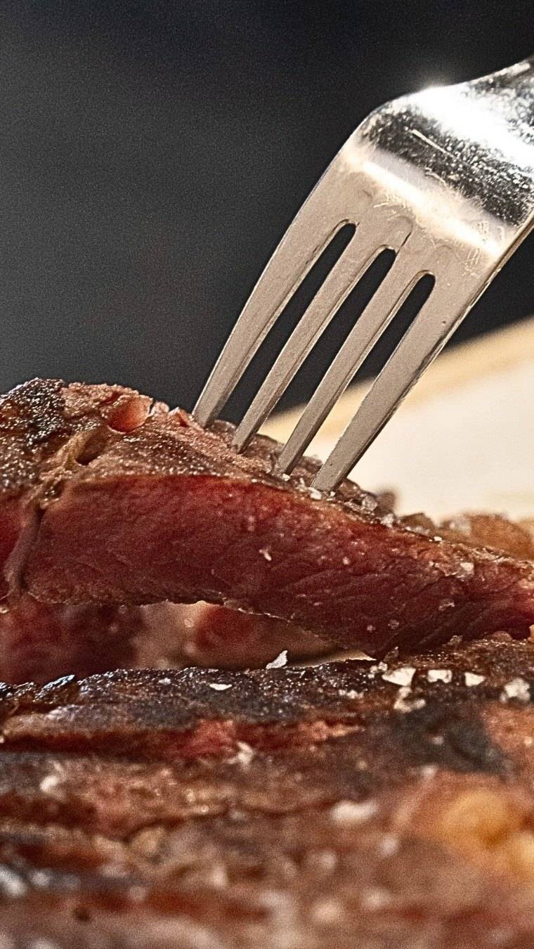 Detalle de un corte de carne madurada pinchado con un tenedor