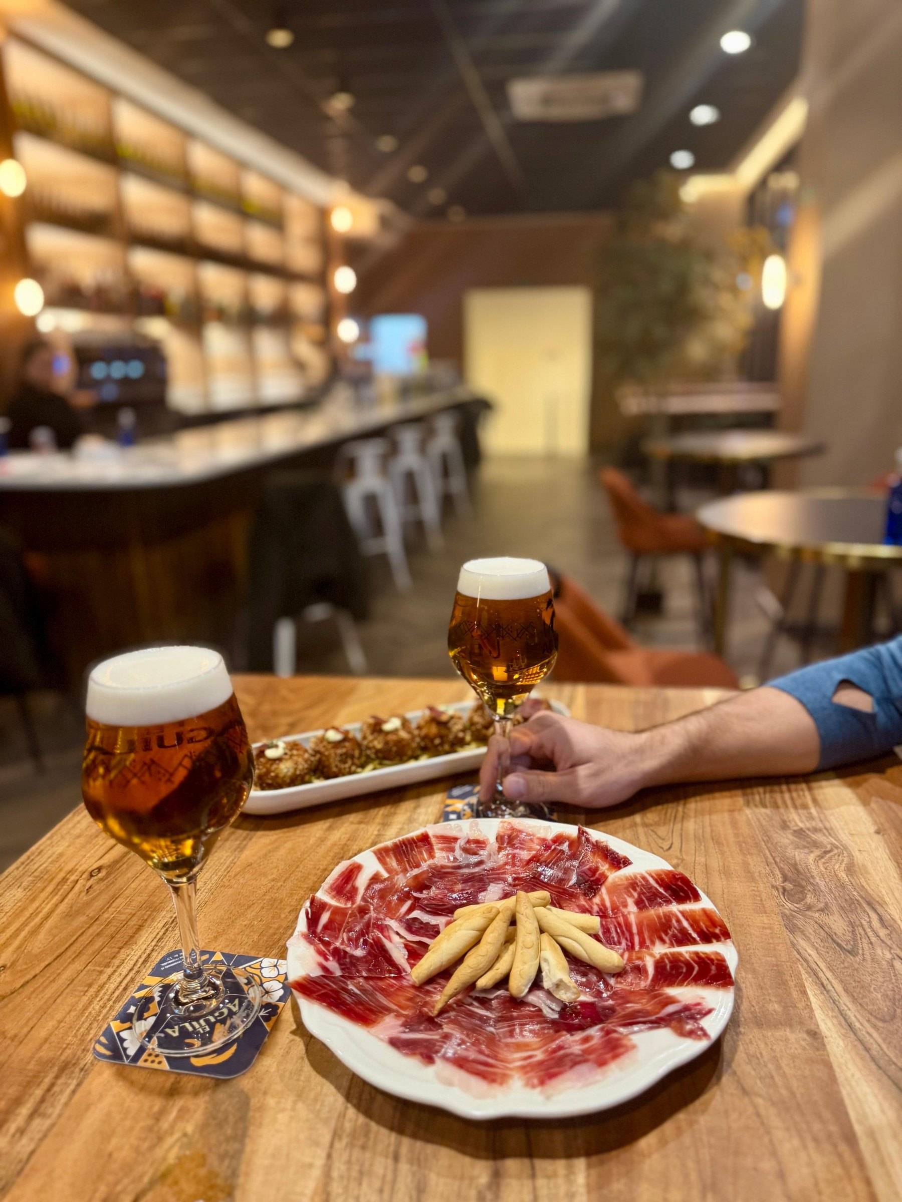Plato de jamón ibérico de bellota con picos y dos cañas en la barra